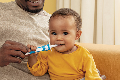Dad and baby practise cleaning teeth together using the MAM Training Brush