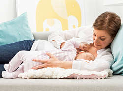 Mother lies on the couch nursing her baby Mother lies on the couch nursing her baby