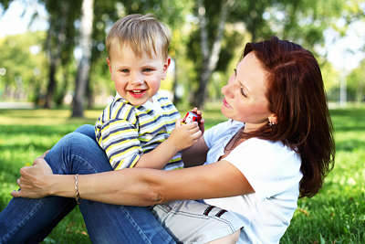 Happy mother sits with her little boy in a meadow