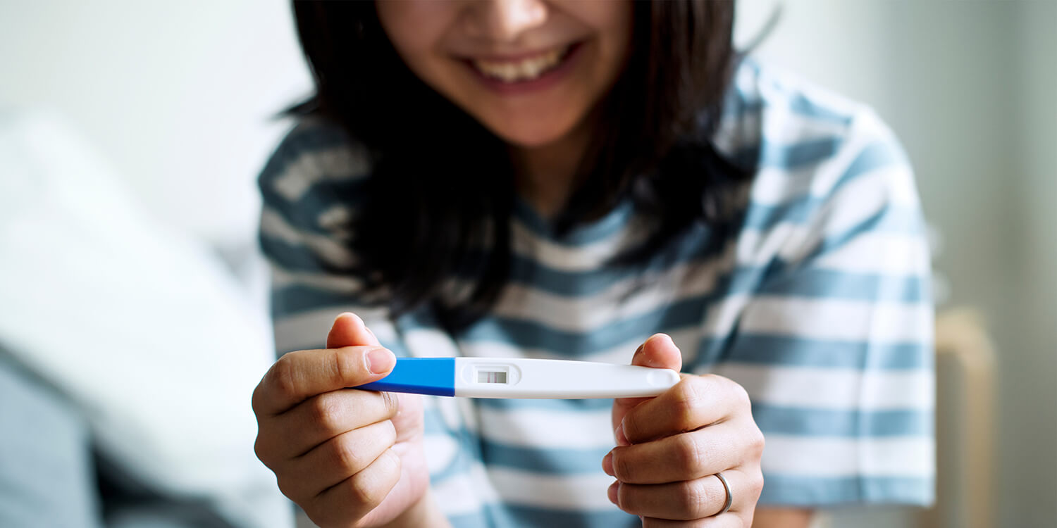 Asiatische Frau mit positivem Schwangerschaftstest