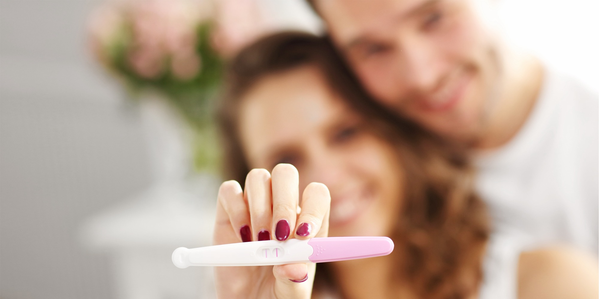 Glad par med graviditetstest i soveværelset 