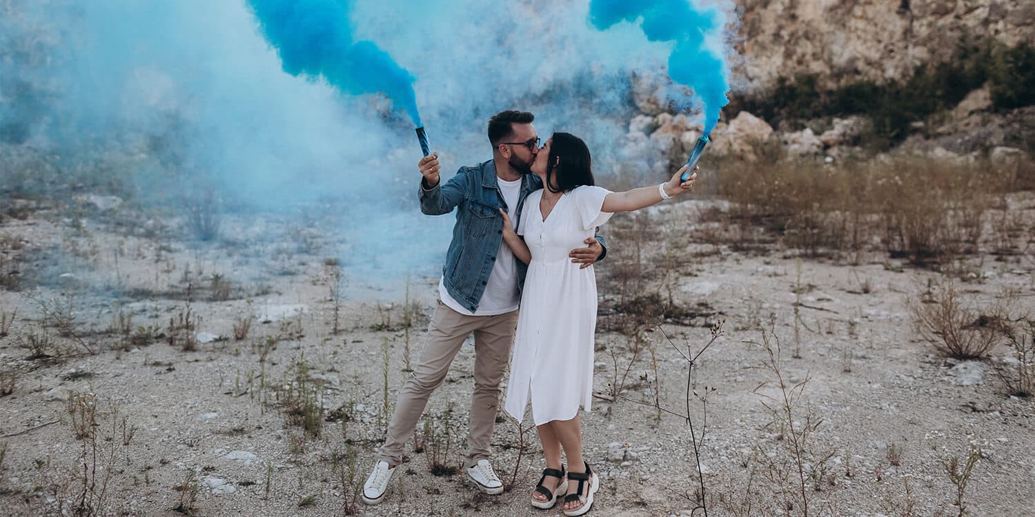 Expectant parents hold up blue smoke cannons to signal that they are having a baby boy. 