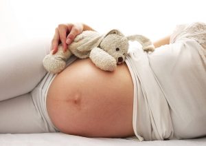 Gravid kvinna med gosedjur på magen