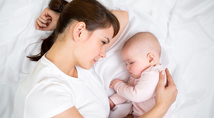 Mamma och baby sover i sängen