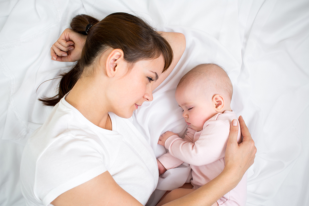 Mamma och baby sover i sängen